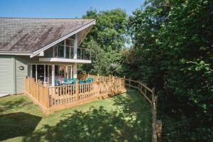 a house with a wooden deck with chairs on it at Trewhiddle Retreat V10 by Together Travel - Luxury 4-Bedroom Villa in St Austell
