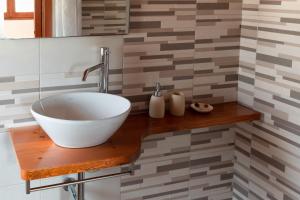 a bathroom with a bowl sink on a wooden shelf at Sa Guardia de Ferricci in Solanas