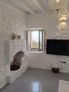 Habitación blanca con TV de pantalla plana en la pared en Oniropagida Nisyros apartment #1, en Nikiá