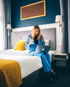 a woman sitting on a bed with a laptop at Villa Art Novis in Wrocław