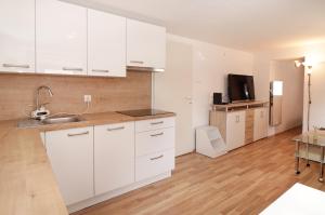 uma cozinha com armários brancos, uma mesa e uma televisão em Spring rest em Bled