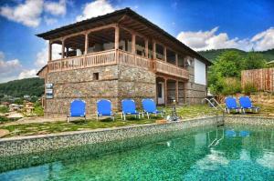 a house with a swimming pool and blue chairs at Панорама хаус Лещен и еко къщи Дървена и Землянка in Leshten