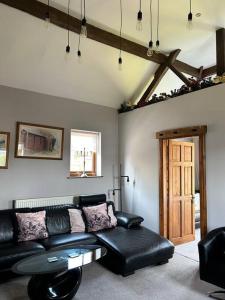 a living room with a black leather couch and a door at Holmleigh Annexe in Tamworth