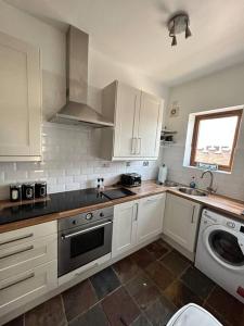 cocina con armarios blancos, fregadero y lavavajillas en Holmleigh Annexe, en Tamworth