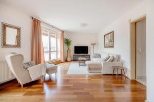 uma sala de estar com mobiliário branco e uma grande janela em Bright and Spacious Penthouse w/ Terrace & Parking em Budapeste