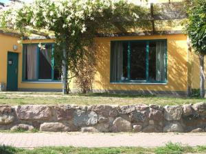 una casa amarilla con una pared de piedra y un árbol en Doppelzimmer 11 Gästehaus Mühlenstein en Bad Sülze