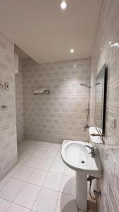 a white bathroom with a sink and a mirror at Radiha Hotel Suites in Al Ḩawīyah