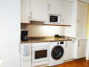 een keuken met witte kasten en een wasmachine en droger bij PARAISO ESTAÑO, Terraza PRIMERA LINEA DE PLAYA in Gijón