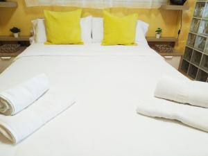 een groot bed met witte lakens en gele kussens bij PARAISO ESTAÑO, Terraza PRIMERA LINEA DE PLAYA in Gijón