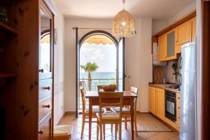 una cucina con tavolo e vista sull'oceano di Residence L'Arcipelago Appartamenti Fronte Mare con Ampio Balcone a Capo dʼOrlando