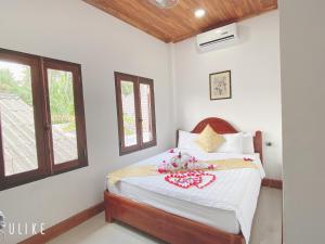 a bedroom with a bed with white walls and windows at Elephant Boutique Hotel in Luang Prabang