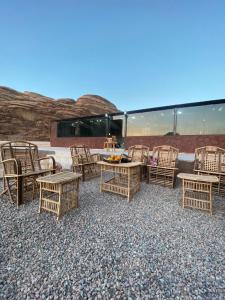 a group of wicker chairs and tables on a patio at Adam Bedouin camp in Wadi Rum