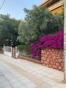 a stone fence with purple flowers on it at Varkiza Lux Apartment in Varkiza