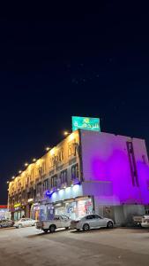 a building with cars parked in front of it at night at Radiha Hotel Suites in Al Ḩawīyah