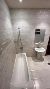 a white bathroom with a tub and a sink at Radiha Hotel Suites in Al Ḩawīyah