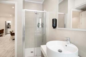baño blanco con ducha y lavamanos en Apartamentos Recaredo 7 , 2ª planta, en Sevilla