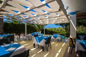 un restaurante con mesas azules y sillas bajo una pérgola en Kampaoh Valledoria, en Valledoria