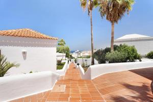 einen Backsteinweg, der zu einem weißen Gebäude mit Palmen führt in der Unterkunft Holiday Valley Blue Ocean B2 in Adeje
