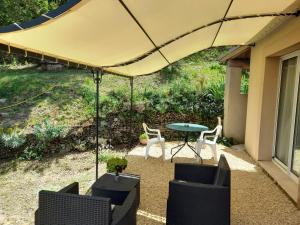 eine Terrasse mit einem Tisch und Stühlen unter einem Sonnenschirm in der Unterkunft Gîte SITTELLE in Malaucène