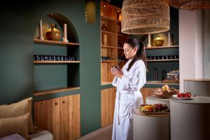 uma mulher de roupão branco em pé numa sala em Panoramahotel Oberjoch em Bad Hindelang