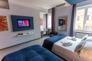 a hotel room with two beds and a flat screen tv at B&B Home 77 in Rome