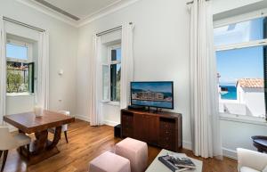 a living room with a tv and two windows at Poseidonion Grand Hotel in Spetses