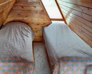 two beds in a wooden cabin with a window at Karemajat Special cottage in Ylitornio