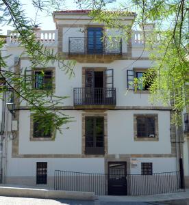 ein Apartmenthaus mit blauen Fenstern und einem Zaun in der Unterkunft Blanco Apartamentos Turísticos in Santiago de Compostela