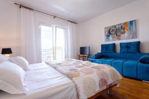 a bedroom with a bed and a blue couch at Apartments Lonzor in Selce