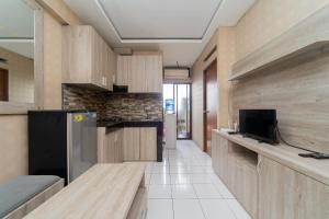 - une cuisine avec des placards en bois et un réfrigérateur noir dans l'établissement RedLiving Apartemen Gateway Cicadas - Sarana Cipta Mahakarya, à Bandung