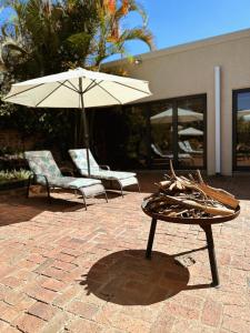 a table with an umbrella next to two chairs at Malcolm Lodge in Kingsmead