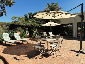 un patio con mesa, sillas y sombrilla en Malcolm Lodge, en Kingsmead