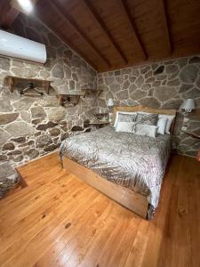 a bedroom with a bed in a stone wall at Casa Largo S Lourenço e Casa da Videira in Mazes