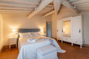 a bedroom with a large white bed and a mirror at Relais Maria Cristina in Chianni