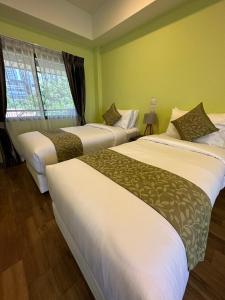 three beds in a room with green walls at The One Sabai Living Pattaya in Pattaya