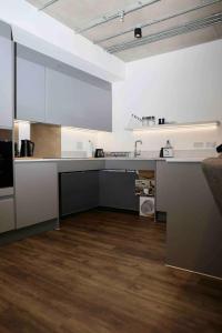 uma grande cozinha com armários brancos e piso em madeira em Charming 3-Bed Apartment in London em Londres