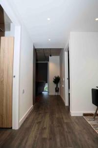 uma sala de estar vazia com paredes brancas e pisos de madeira em Charming 3-Bed Apartment in London em Londres