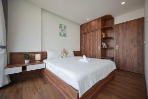 Schlafzimmer mit einem großen weißen Bett und Holzschränken in der Unterkunft Sweethome 121 Yen Phu Westlake Apartment in Hanoi