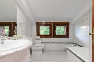 a white bathroom with a tub and a toilet and a sink at Ezkialderdi - baskeyrentals in Aia