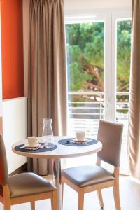 a table with two cups and chairs and a window at ZENAO Fréjus in Fréjus