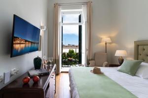 Cette chambre comprend un lit et une grande fenêtre. dans l'établissement Poseidonion Grand Hotel, à Spetses