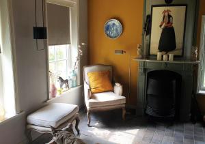 a living room with a chair and a fireplace at Fakânsjehûs Sfeervol met fijne tuin in Irnsum