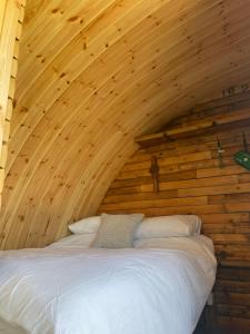 una camera con un letto su una parete in legno di Henny Riverside Glamping a Sudbury