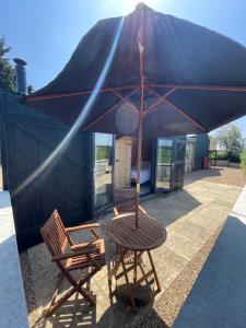 une table et deux chaises sous un parasol dans l'établissement Henny Riverside Glamping, à Sudbury