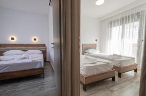 a bedroom with two beds and two windows at Chryssis Village by Travel Pro Services - Nea Potidaia Halkidiki in Nea Potidaea