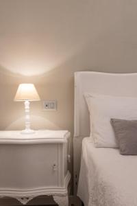 ein weißes Bett mit einer weißen Lampe auf einem Nachttisch in der Unterkunft BeB San Lorenzo in Bergamo