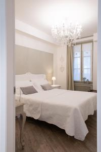 a white bedroom with a large bed and a chandelier at BeB San Lorenzo in Bergamo