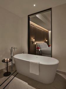 a white bath tub in a bathroom with a mirror at The Abu Dhabi EDITION in Abu Dhabi