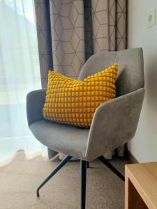 a yellow pillow sitting on a grey chair at Pension Gabl in Pfunds