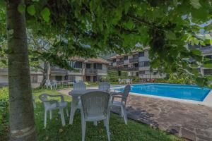 a table and chairs under a tree next to a swimming pool at Blu al Lago in Lierna